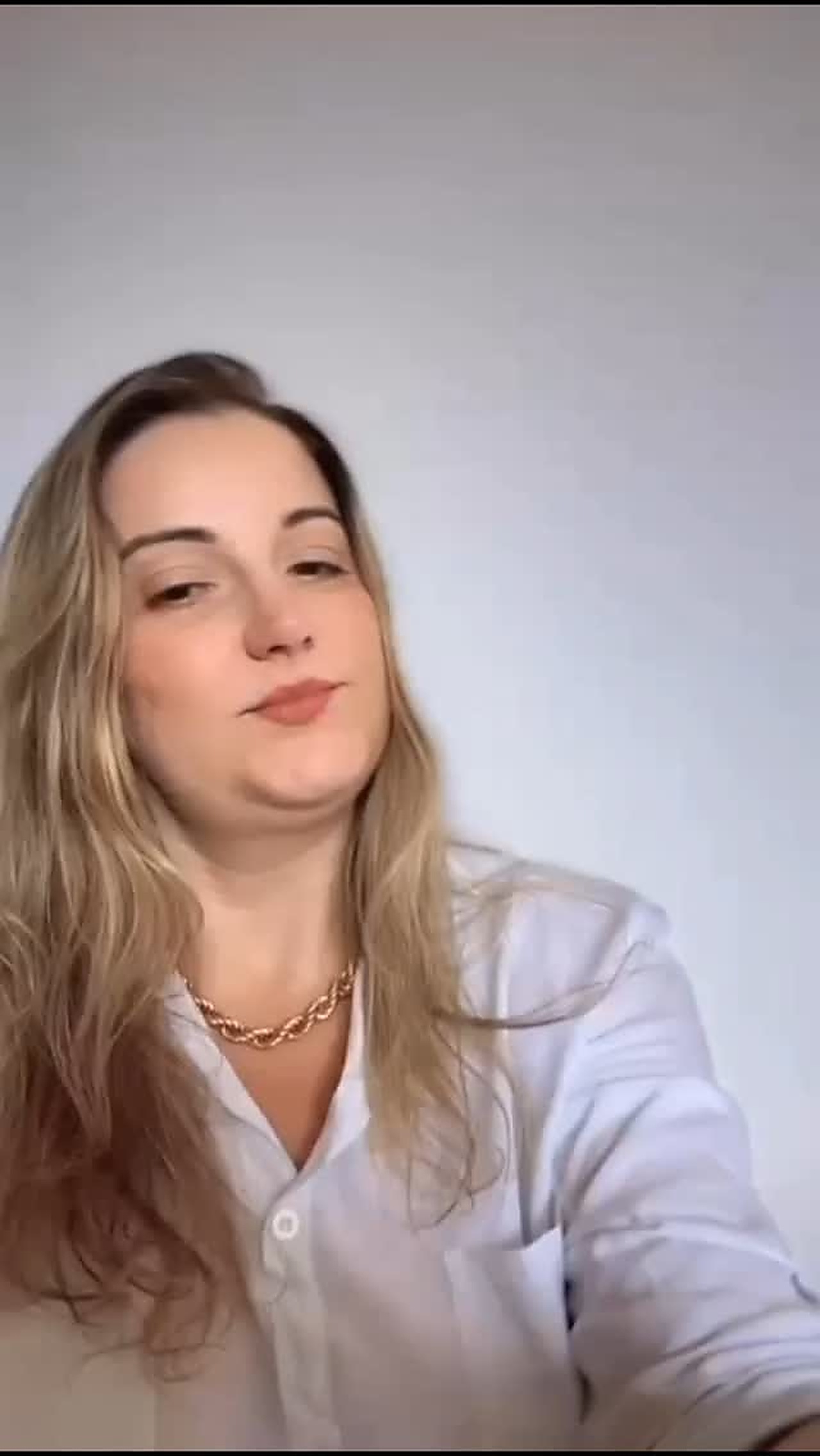 Retrato da Dra. Silvana Konradt com fundo neutro e a mão próxima ao queixo, em pose reflexiva